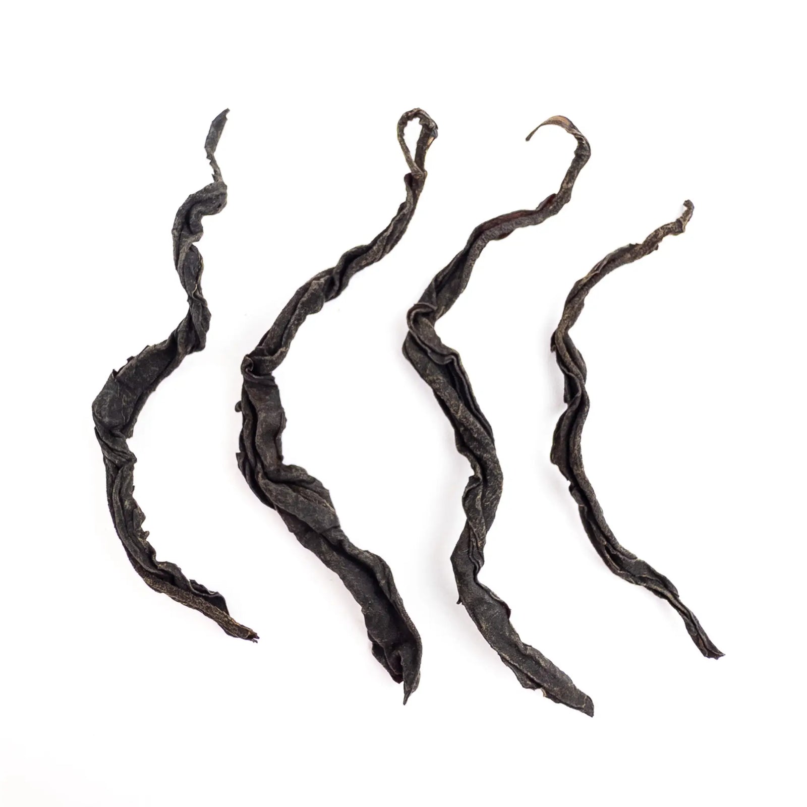 Four twisted black tea leaves on a white background