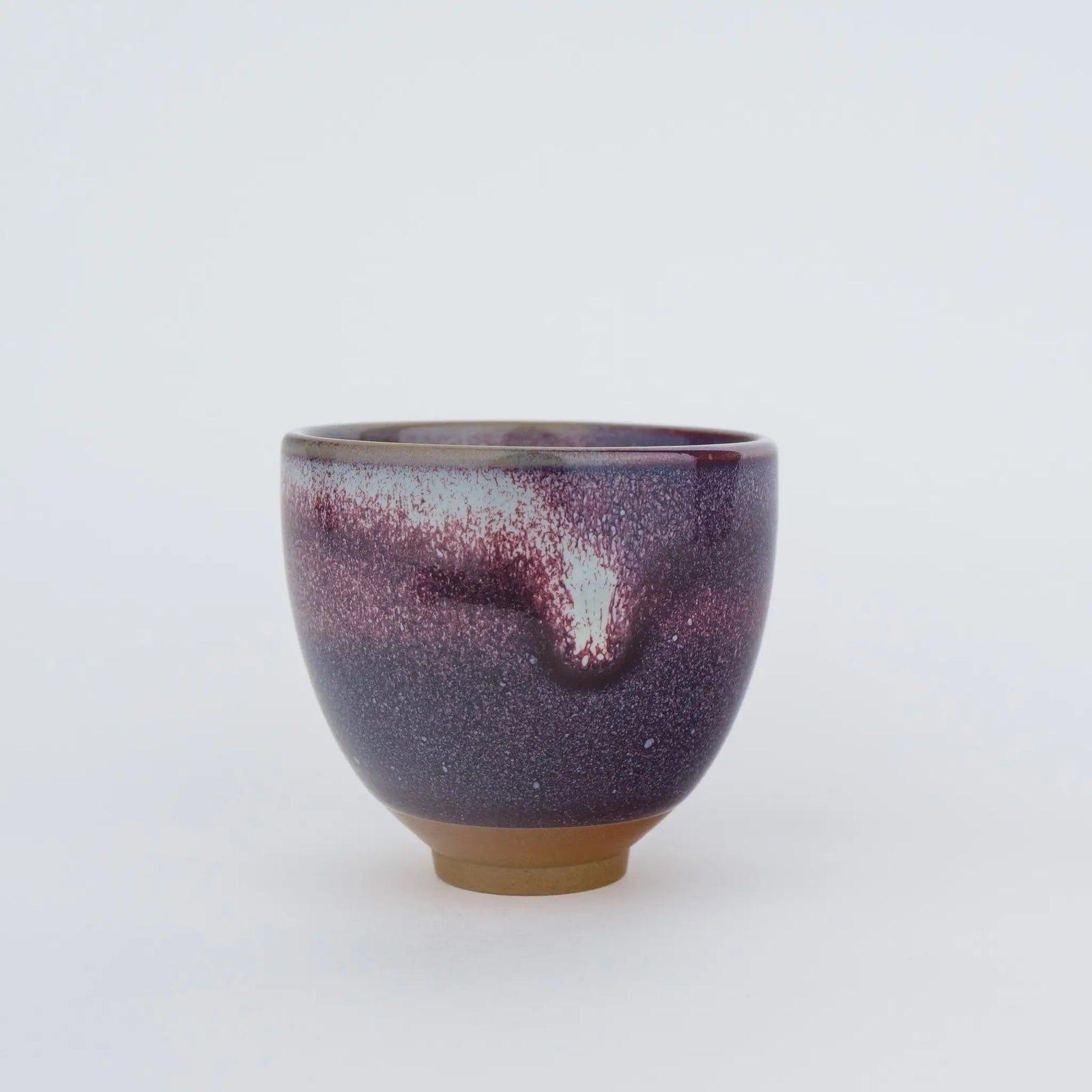 Purple ceramic cup with speckled texture on a white background