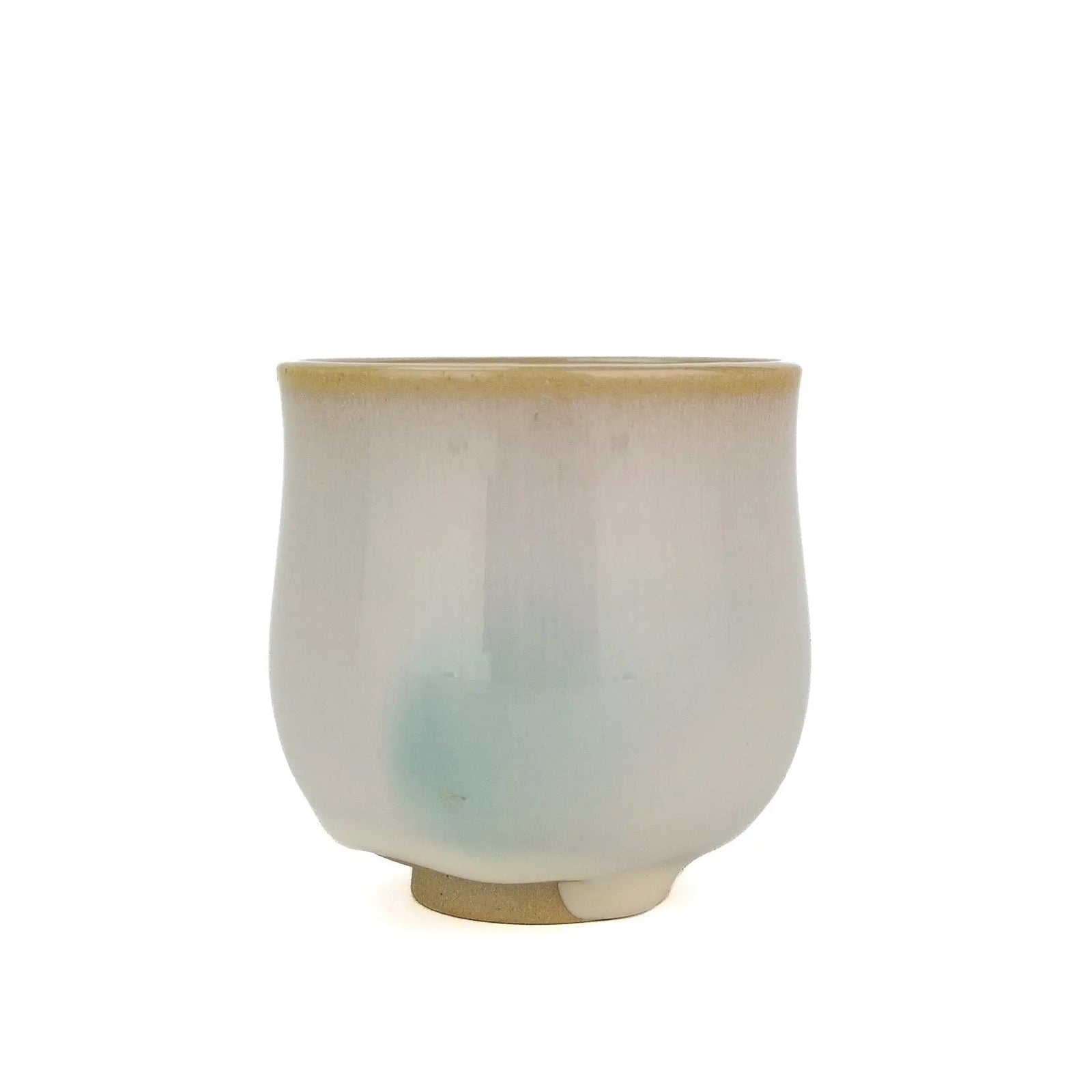 Huaning handmade cup #352, a tall rounded cup in white glaze with a blue-green patch near the base and a tan rim