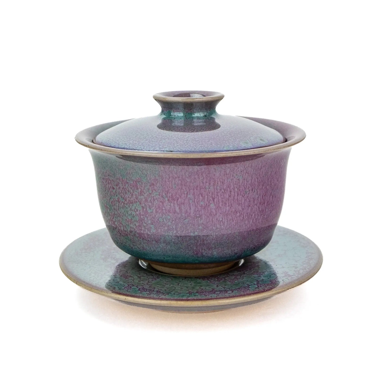 A ceramic handmade gaiwan with a matching saucer, featuring a speckled glaze that transitions from teal green to deep magenta , set against a plain white background.