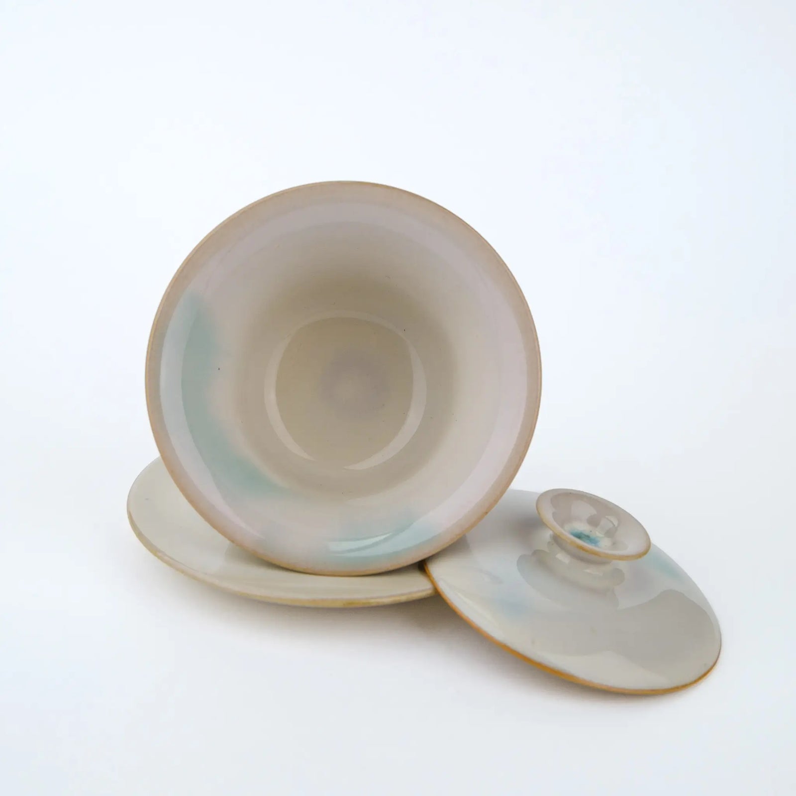 Huaning gaiwan #401 bowl tipped on its saucer next to the lid, showing a blue-green streak inside