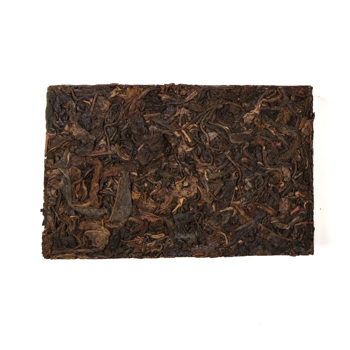 Rectangular block of dark brown tea leaves on a white background