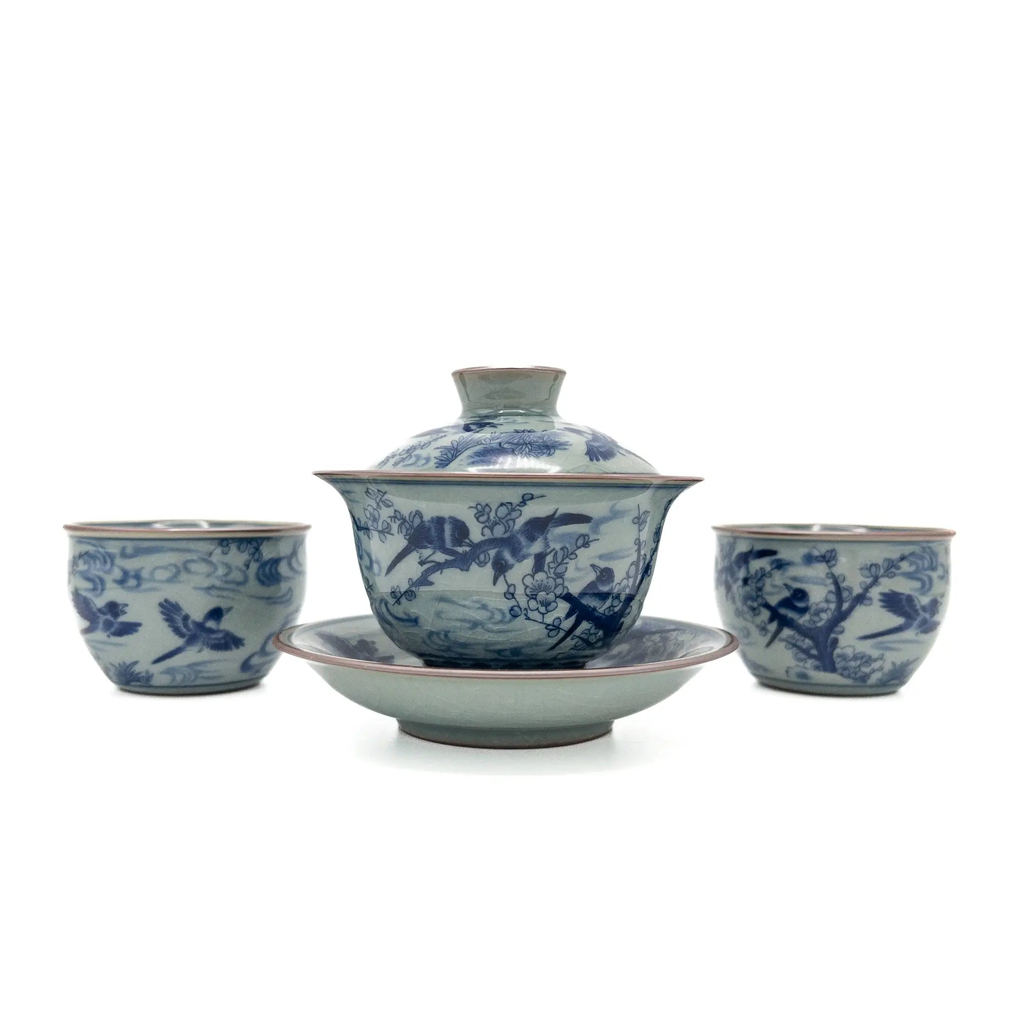 Blue and celadon-toned porcelain gaiwan set with lid, saucer, and two matching teacups featuring hand-painted birds and plum blossoms