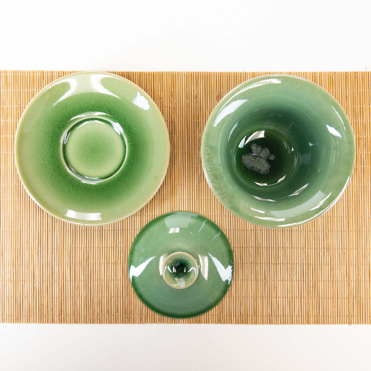 Green ceramic gaiwan with lid on a bamboo mat
