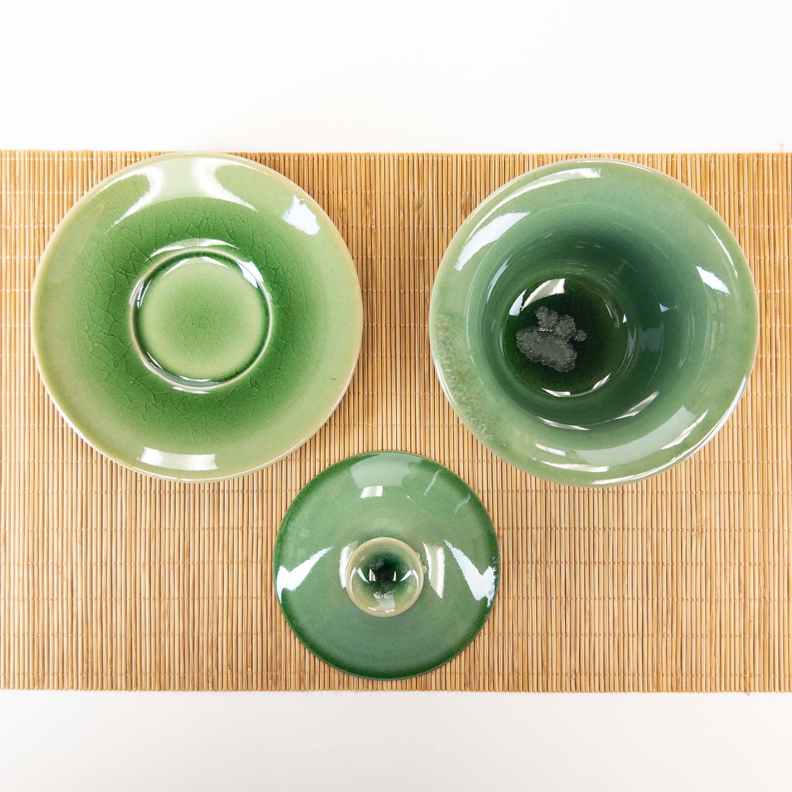 Green ceramic gaiwan with lid on a bamboo mat
