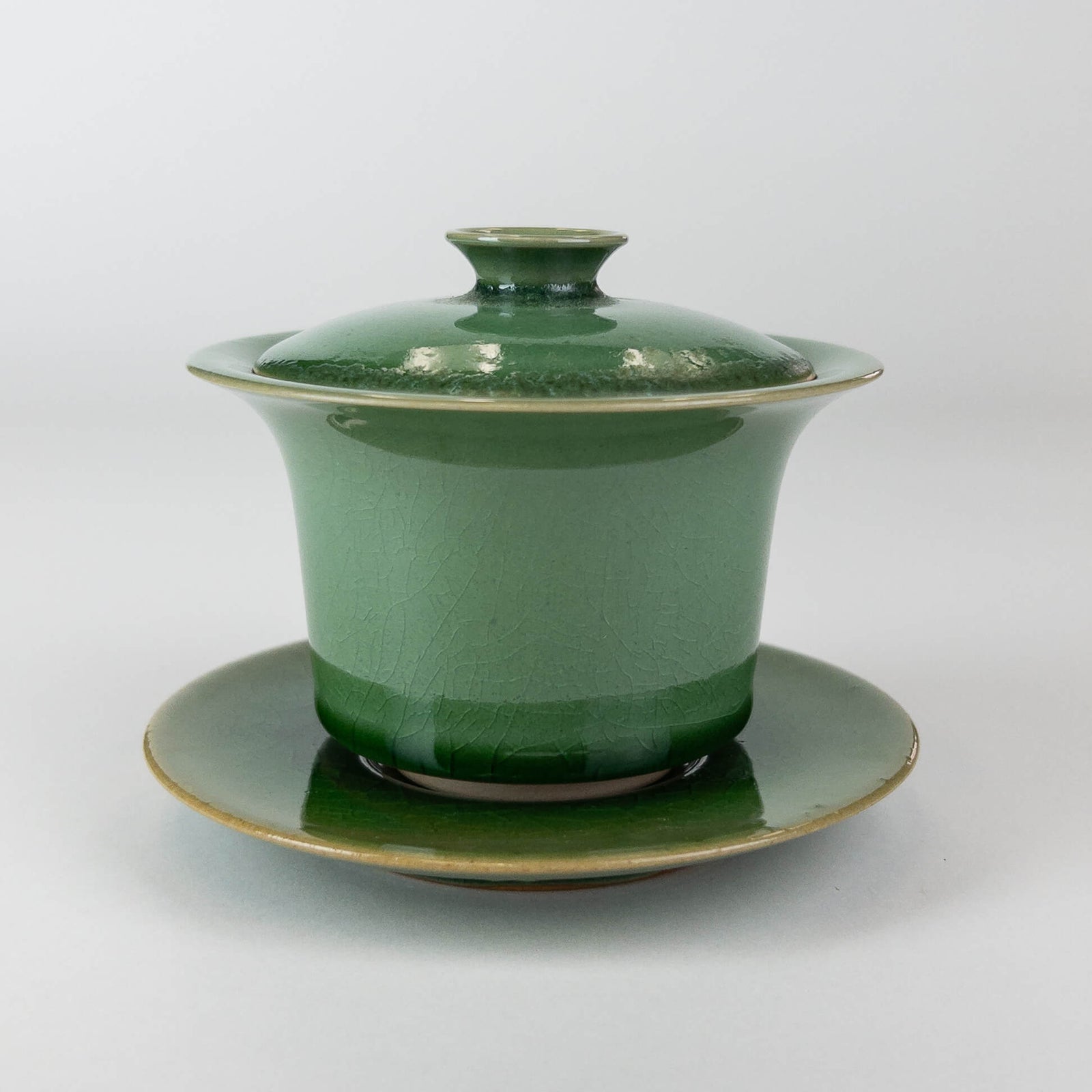 Green ceramic gaiwan with lid on a white background
