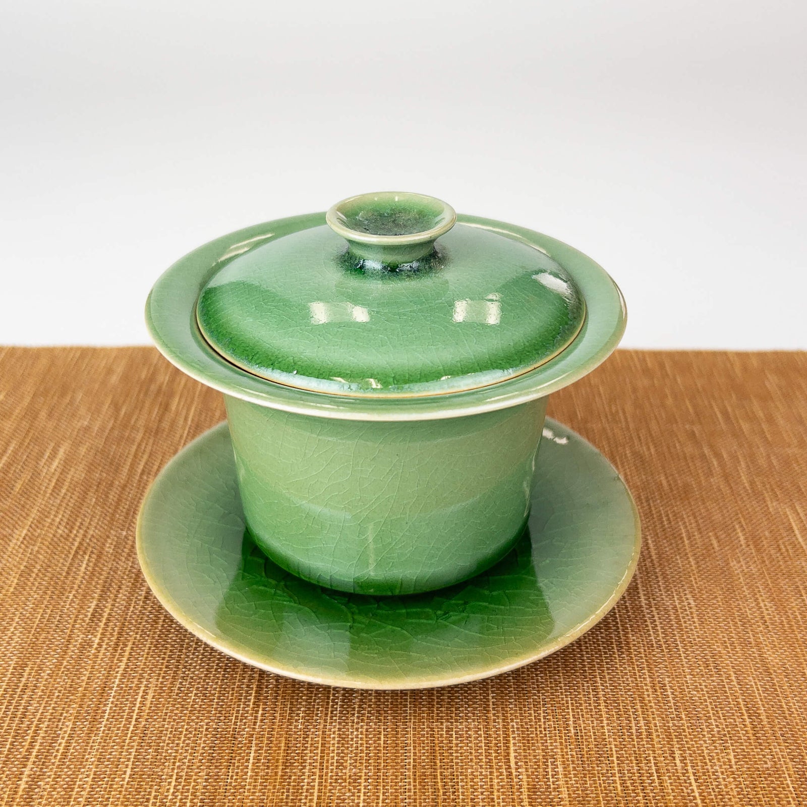 Green ceramic gaiwan with lid on a bamboo mat