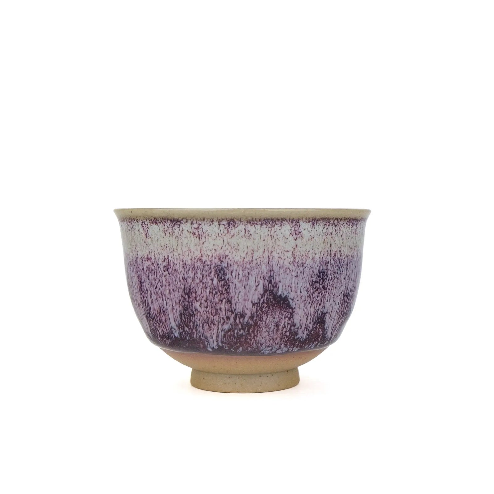 A ceramic tea handmade teacup with a purple and white glaze pattern and a natural beige clay base, shown against a plain white background.