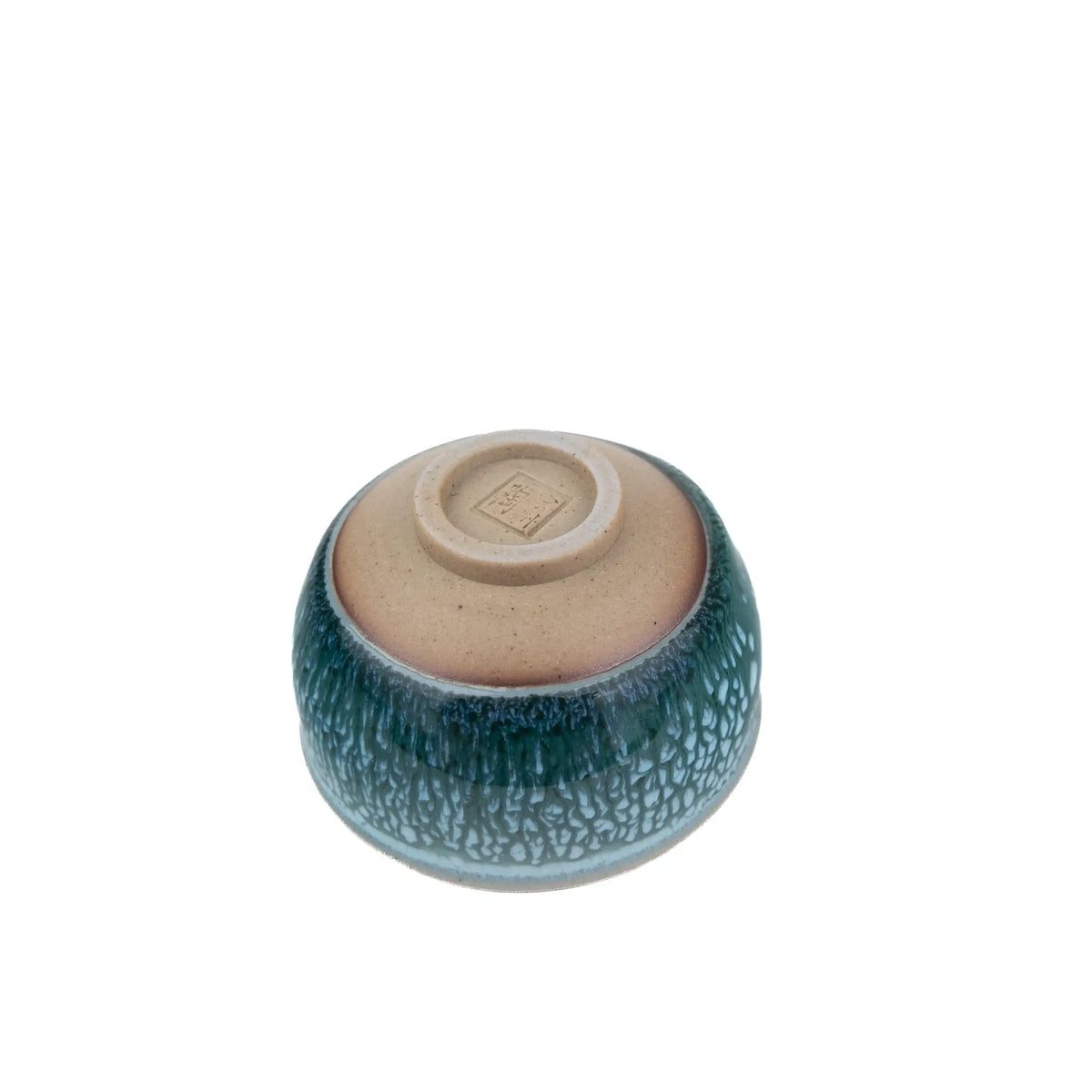 A small ceramic teacup with a textured, crackled glaze in deep teal-green and light blue, featuring a contrasting matte beige interior visible from the bottom.
