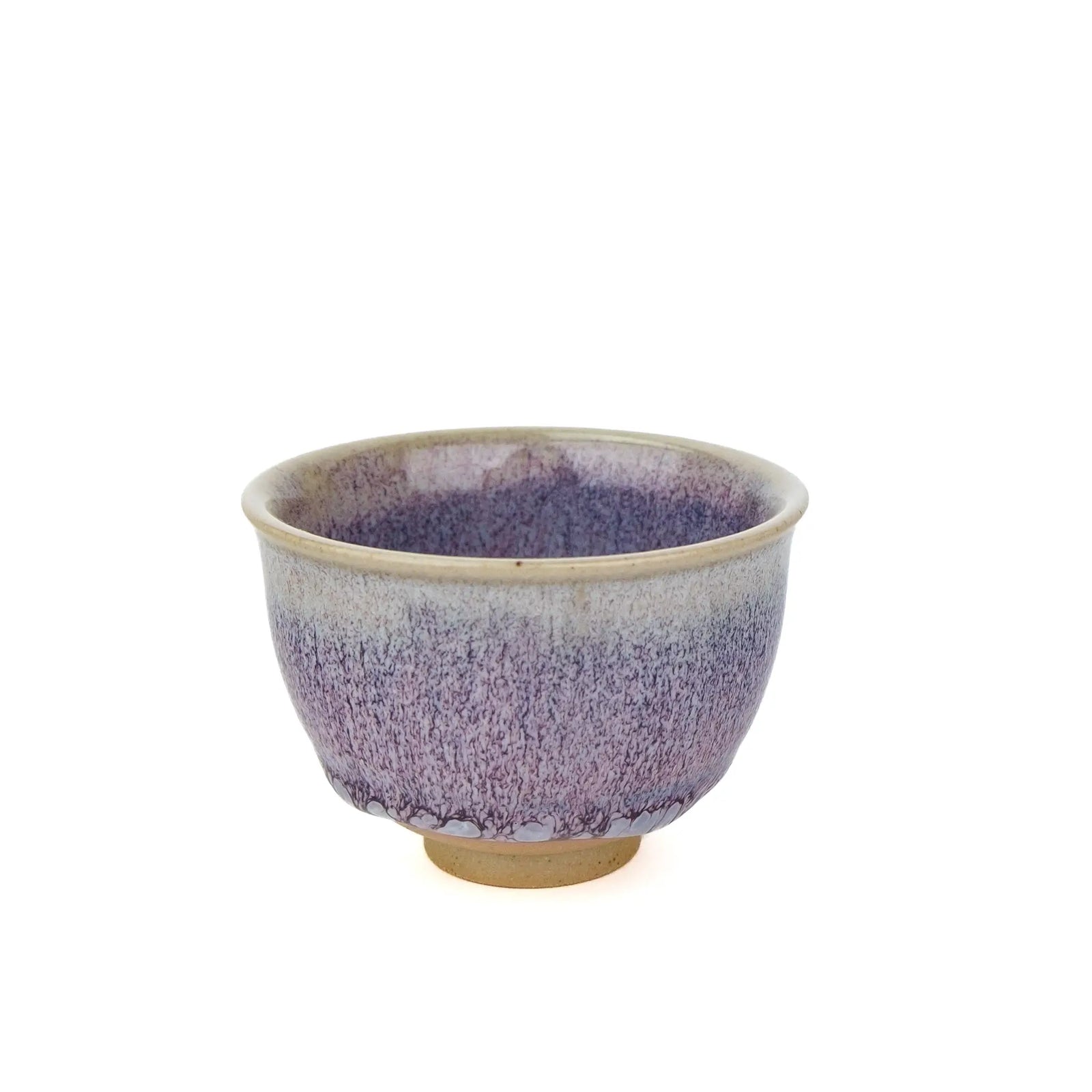 A ceramic tea cup with a purple and blue speckled glaze that fades to a beige rim and base, shown on a plain white background.