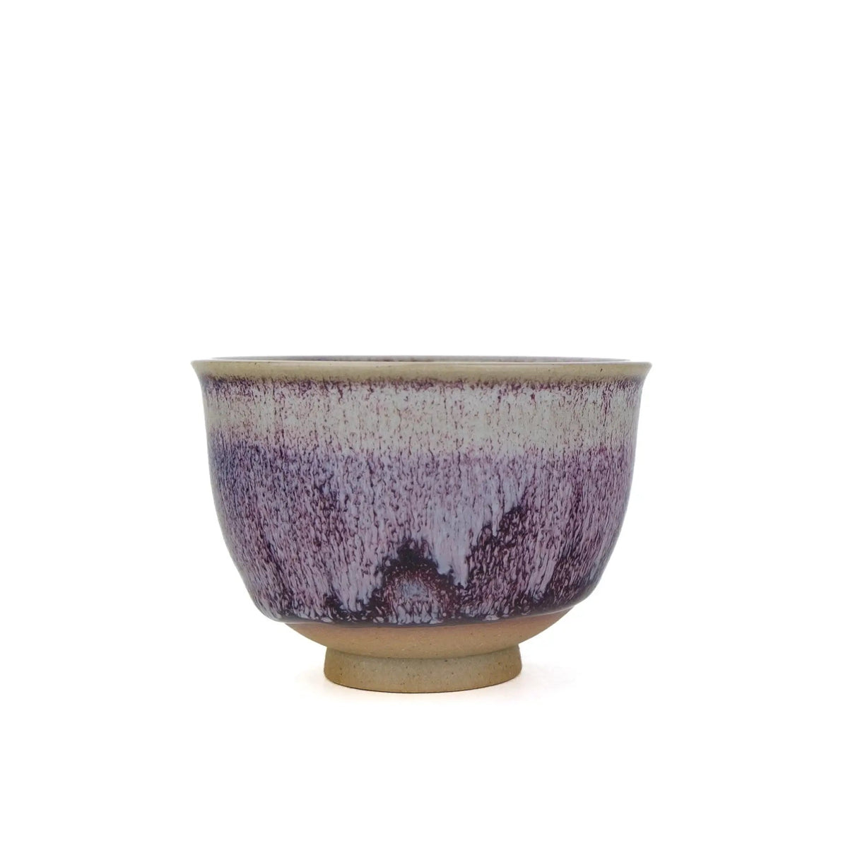 A ceramic tea handmade teacup with a purple and white glaze pattern and a natural beige clay base, shown against a plain white background.