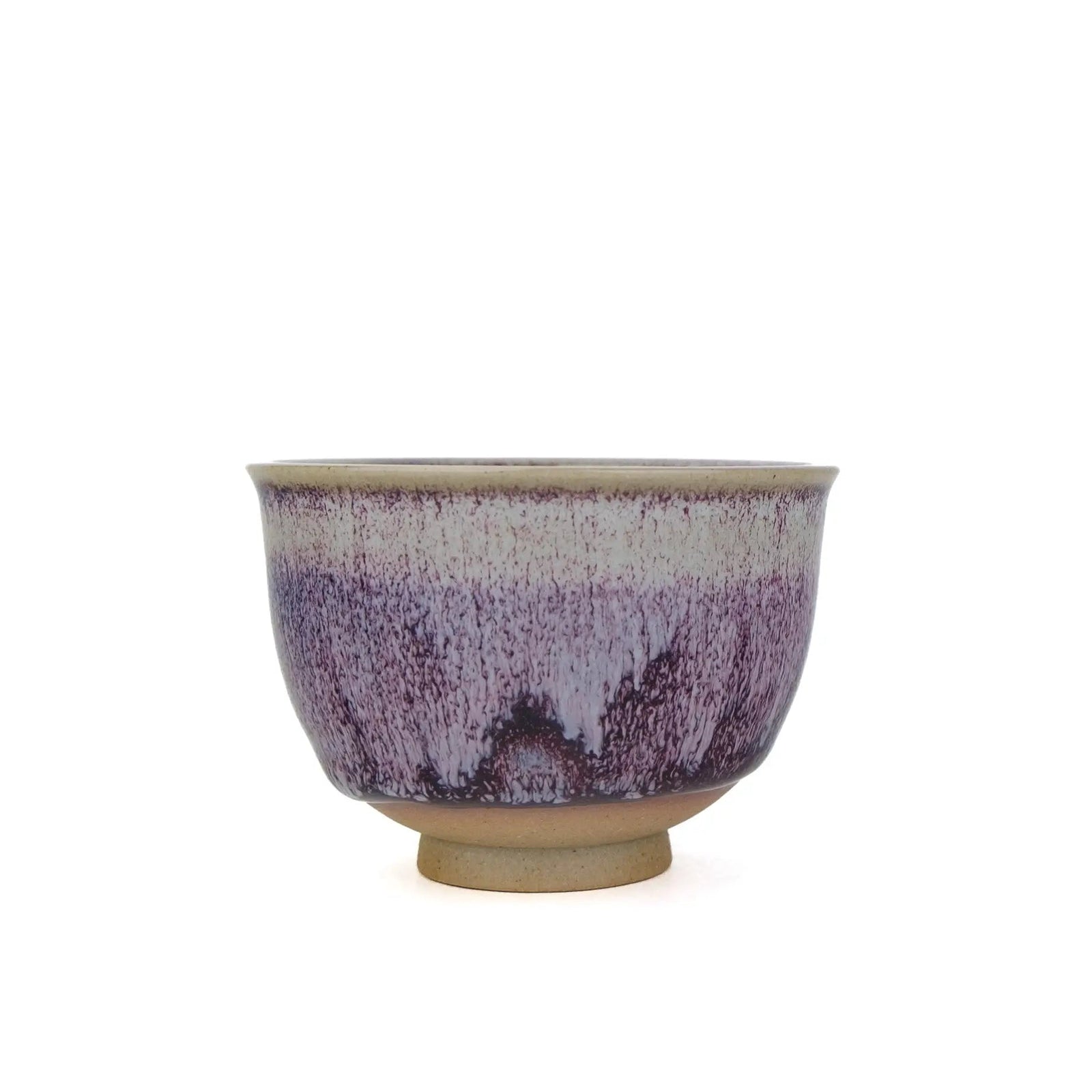 A ceramic tea handmade teacup with a purple and white glaze pattern and a natural beige clay base, shown against a plain white background.