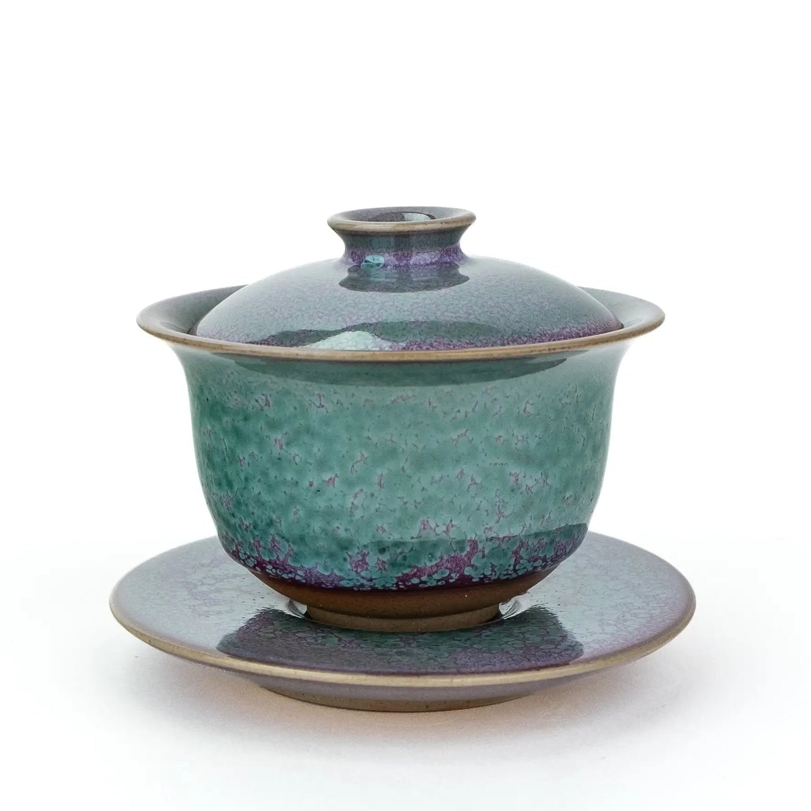 A handmade gaiwan with a matching saucer, featuring a speckled teal and purple glaze against a plain white background.