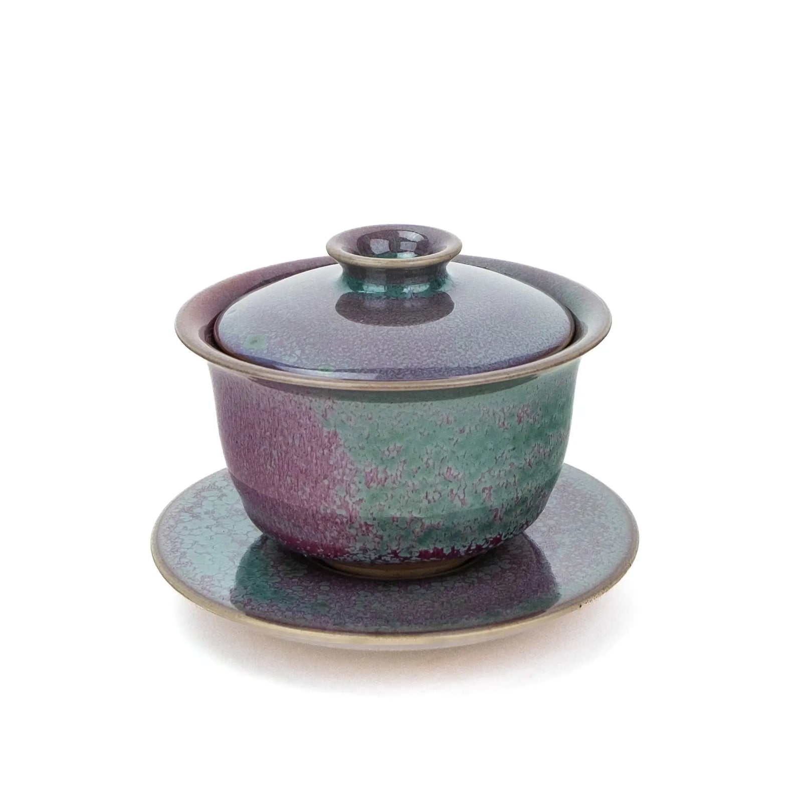 A ceramic handmade gaiwan with a matching saucer, featuring a speckled glaze that transitions from teal green to deep magenta , set against a plain white background.