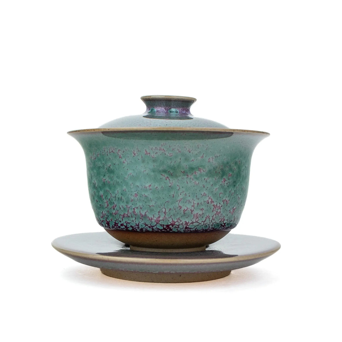 A handmade gaiwan with a matching saucer, featuring a speckled teal and purple glaze against a plain white background.
