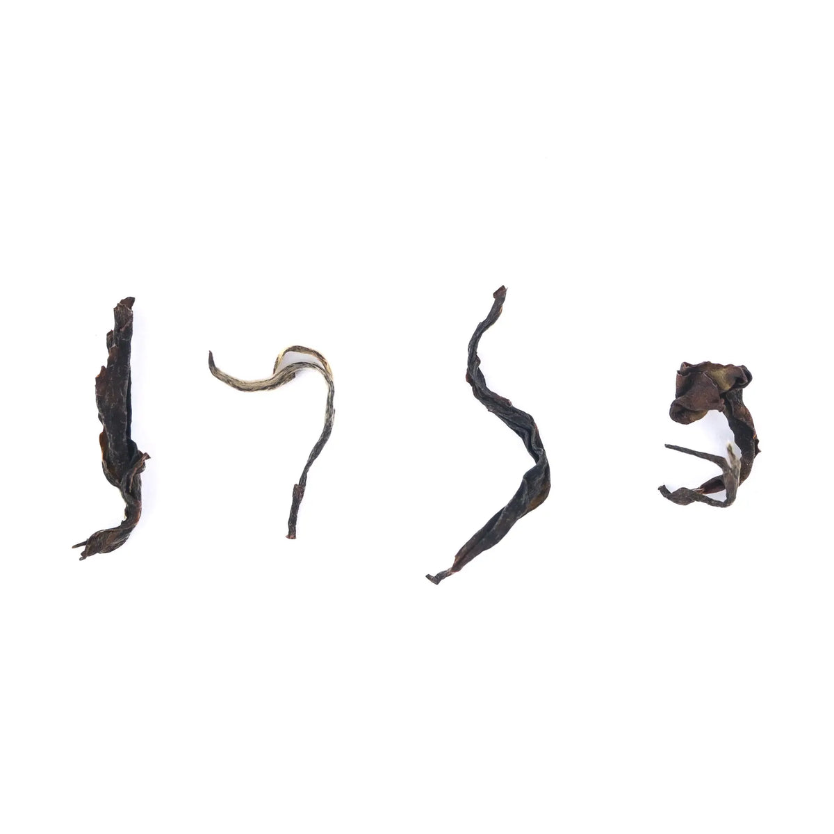 Four dried tea leaves of different shapes on a white background - Winter Cloud - Black Tea from Lakyrsiew Estate