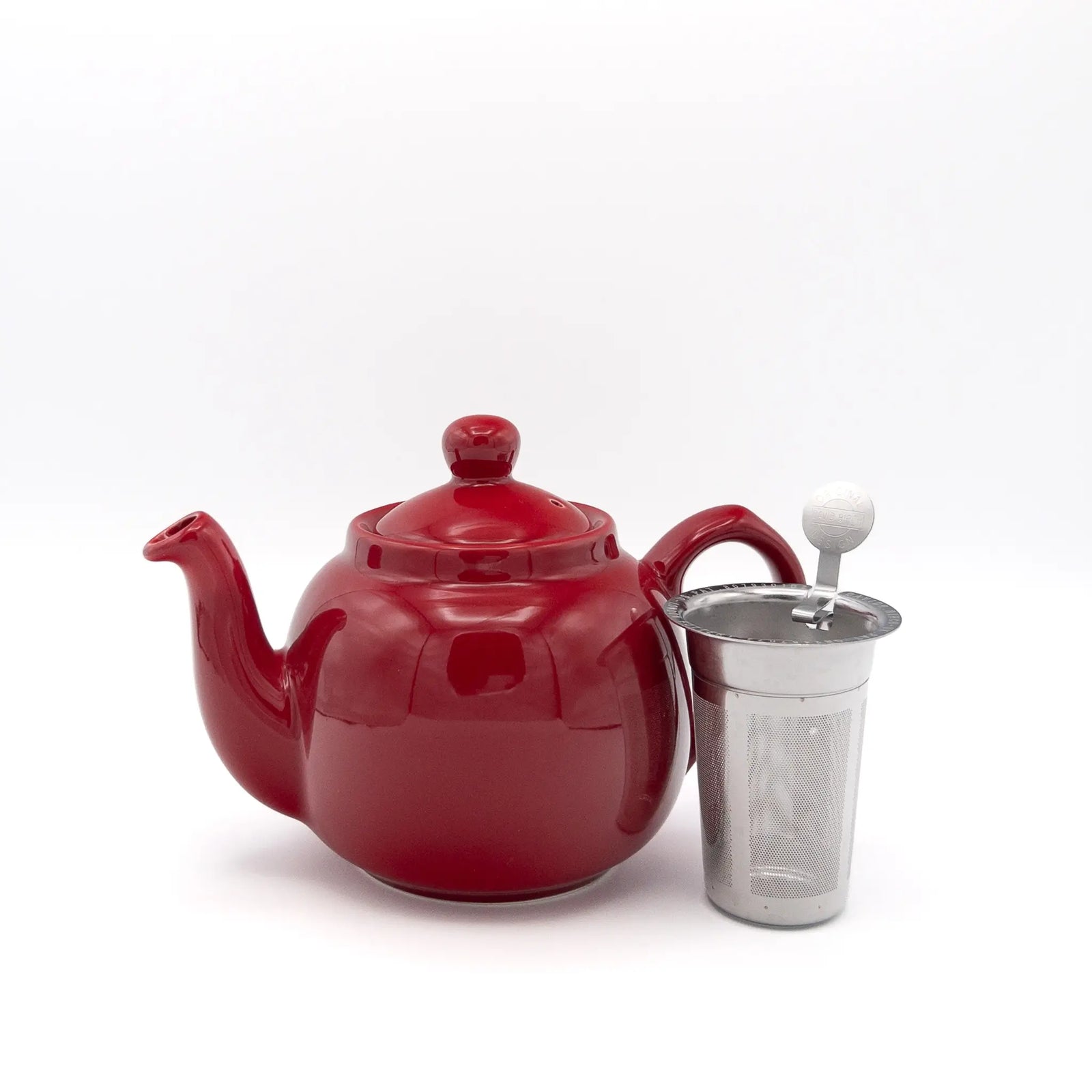 A glossy red ceramic teapot with a matching lid and a stainless steel infuser  set against a plain white background.