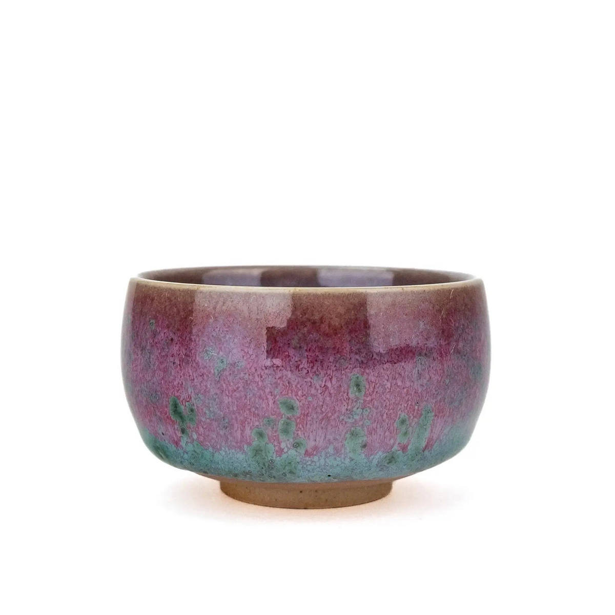 A handmade ceramic teacup with a glossy glaze featuring a gradient of purple, pink, and teal-green, with a natural brown clay base, set against a plain white background.