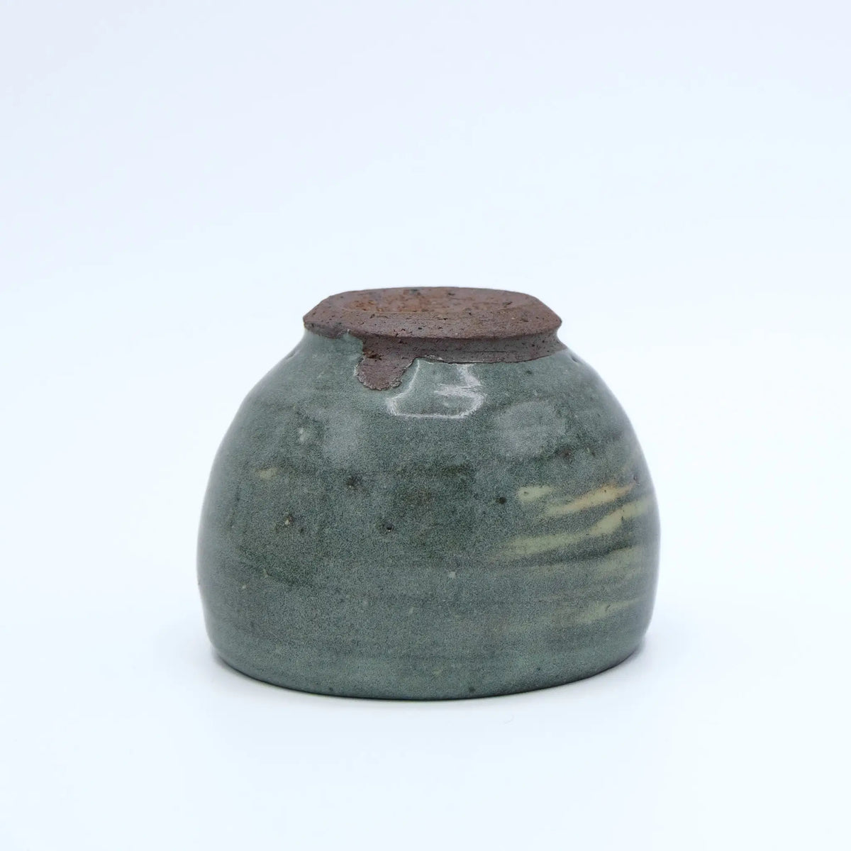 Greenish ceramic cup with striped pattern on a white background