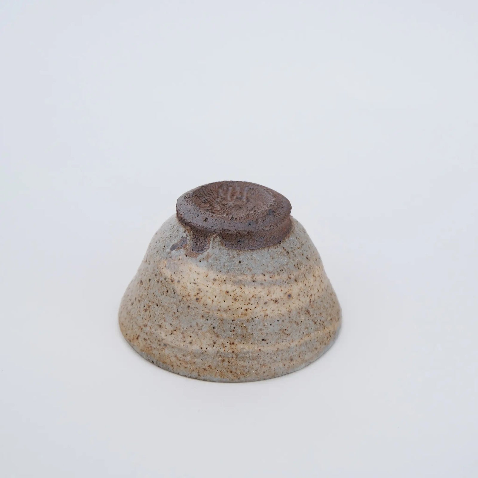 Ceramic teacup with speckled texture on a white background - underside view