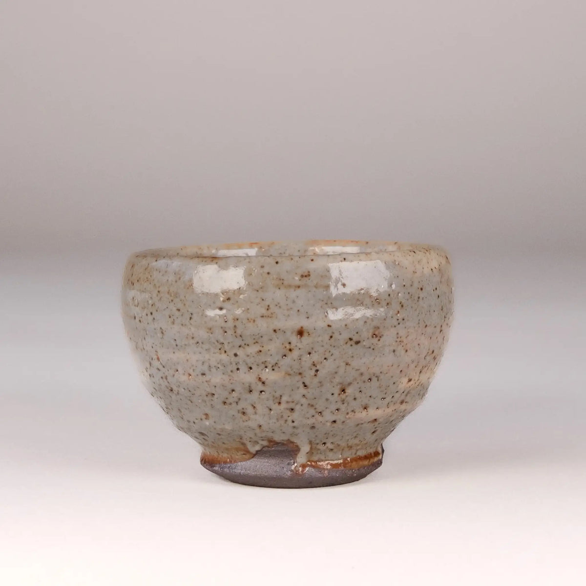 Ceramic handmade tea cup with speckled glaze on a plain background