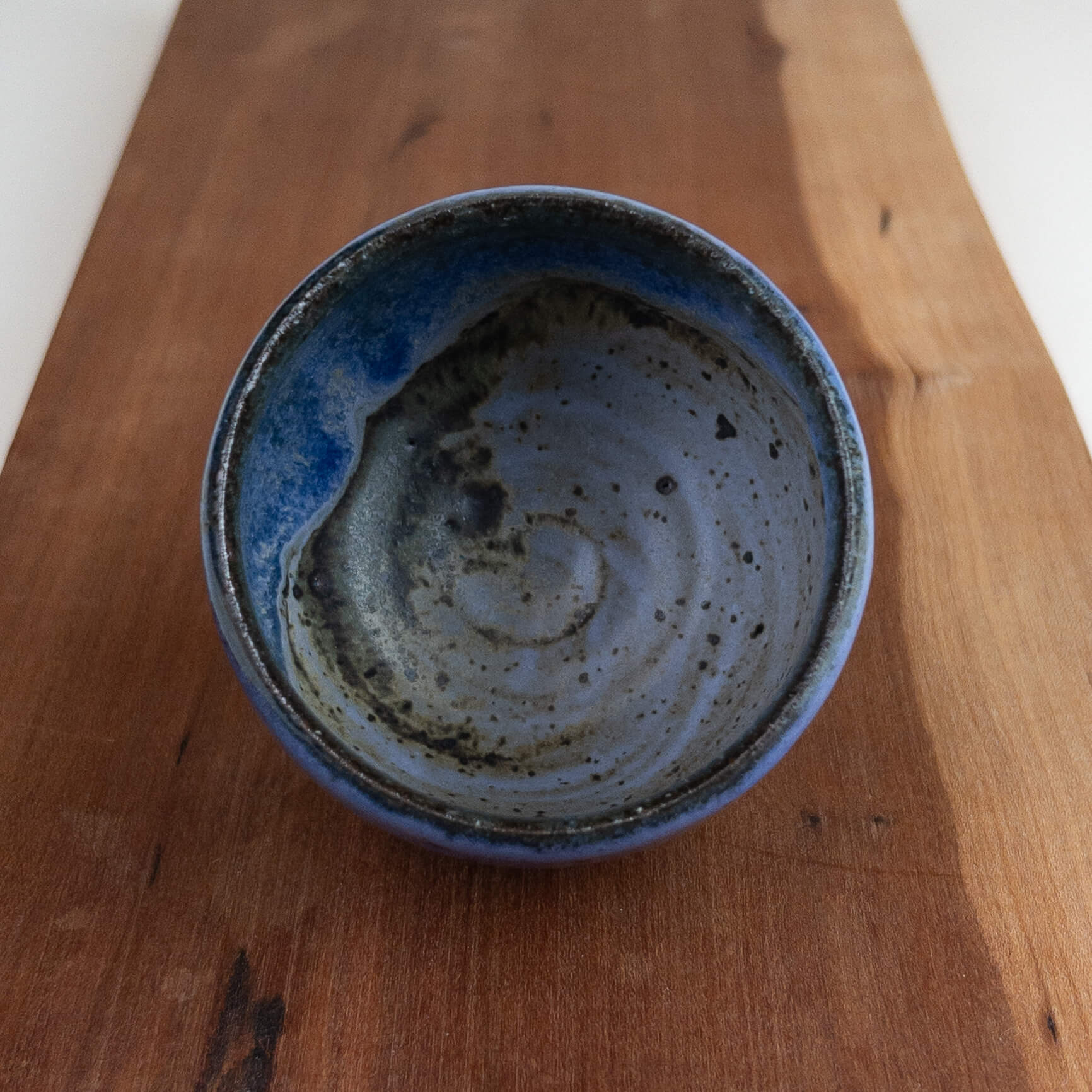 Blue ceramic cup with a swirling pattern on a wooden surface