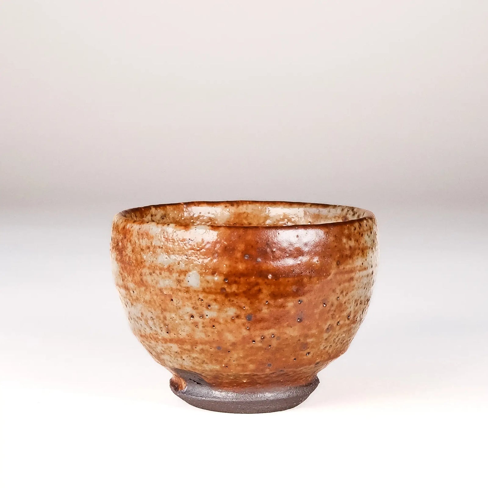 Ceramic cup with speckled glaze on a plain background