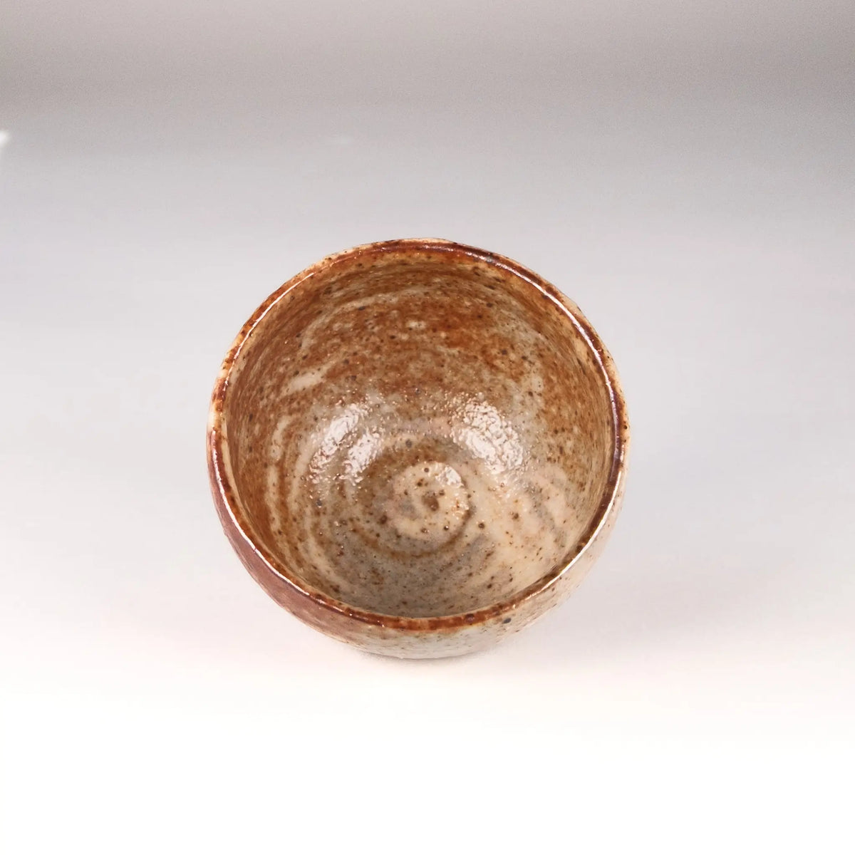 Ceramic cup with speckled glaze on a plain background