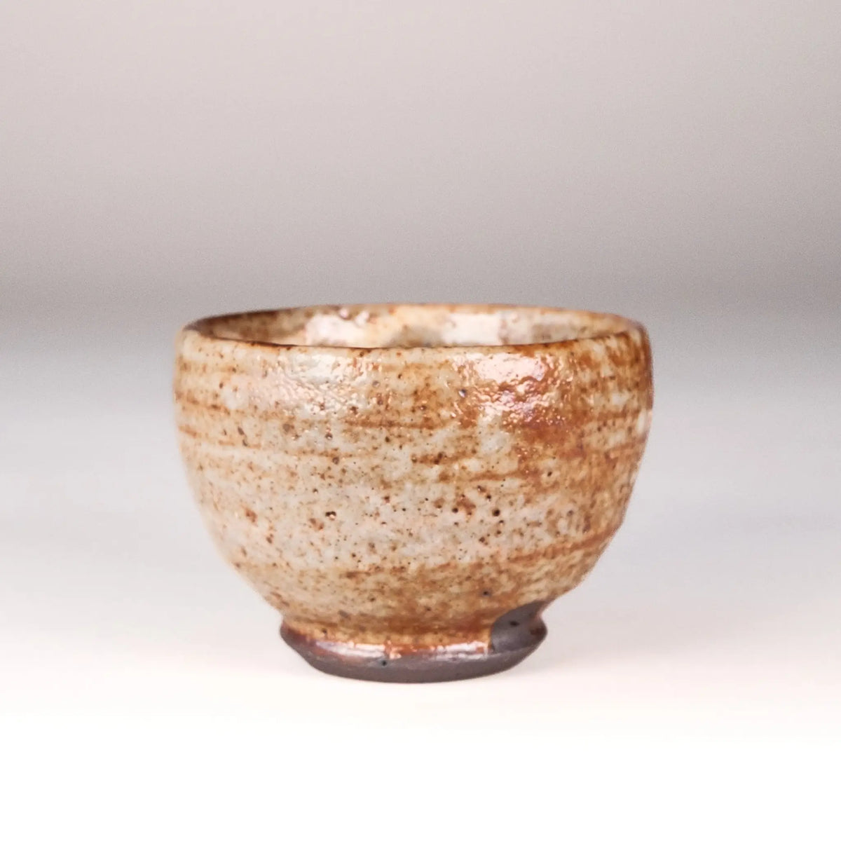 Ceramic cup with speckled glaze on a plain background