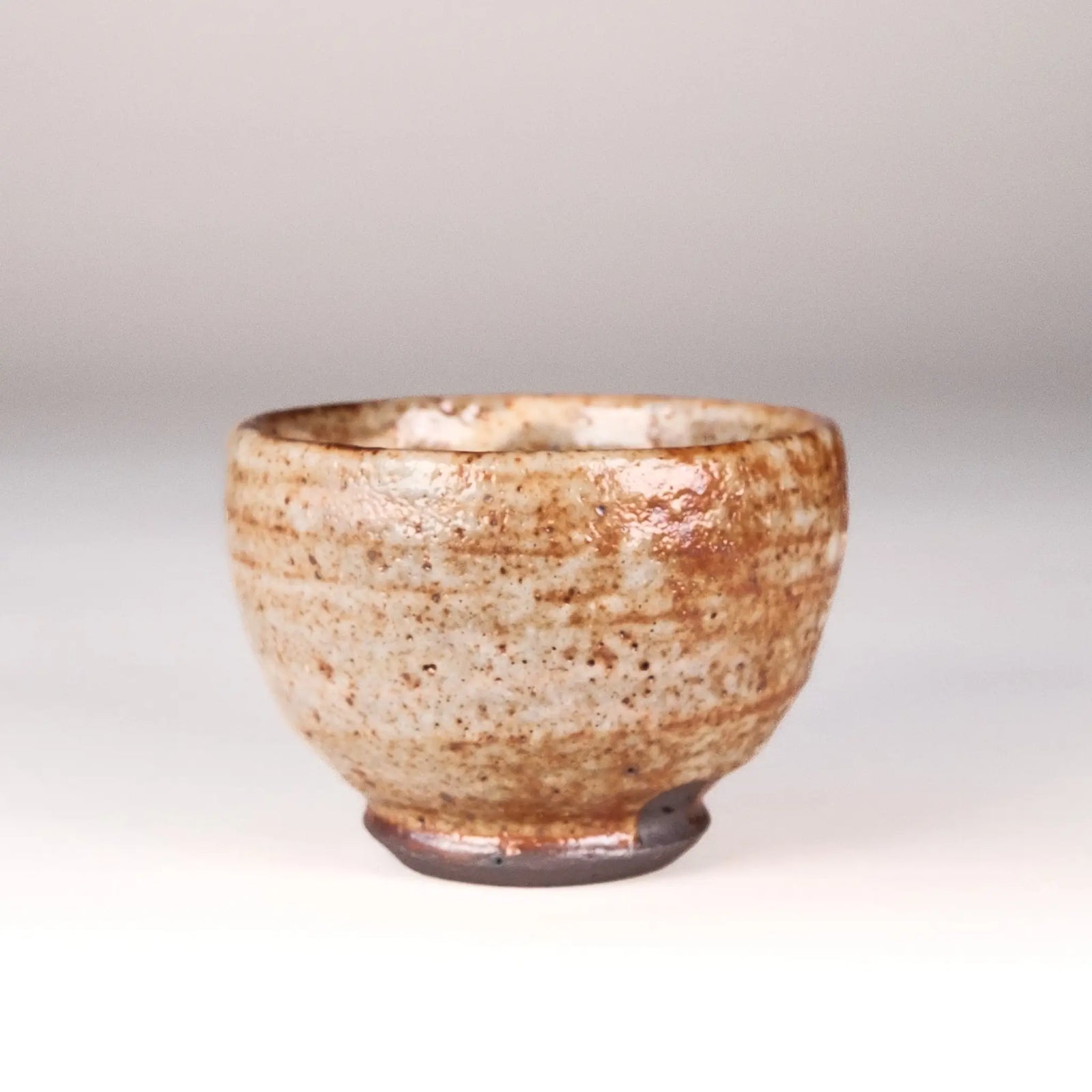 Ceramic cup with speckled glaze on a plain background