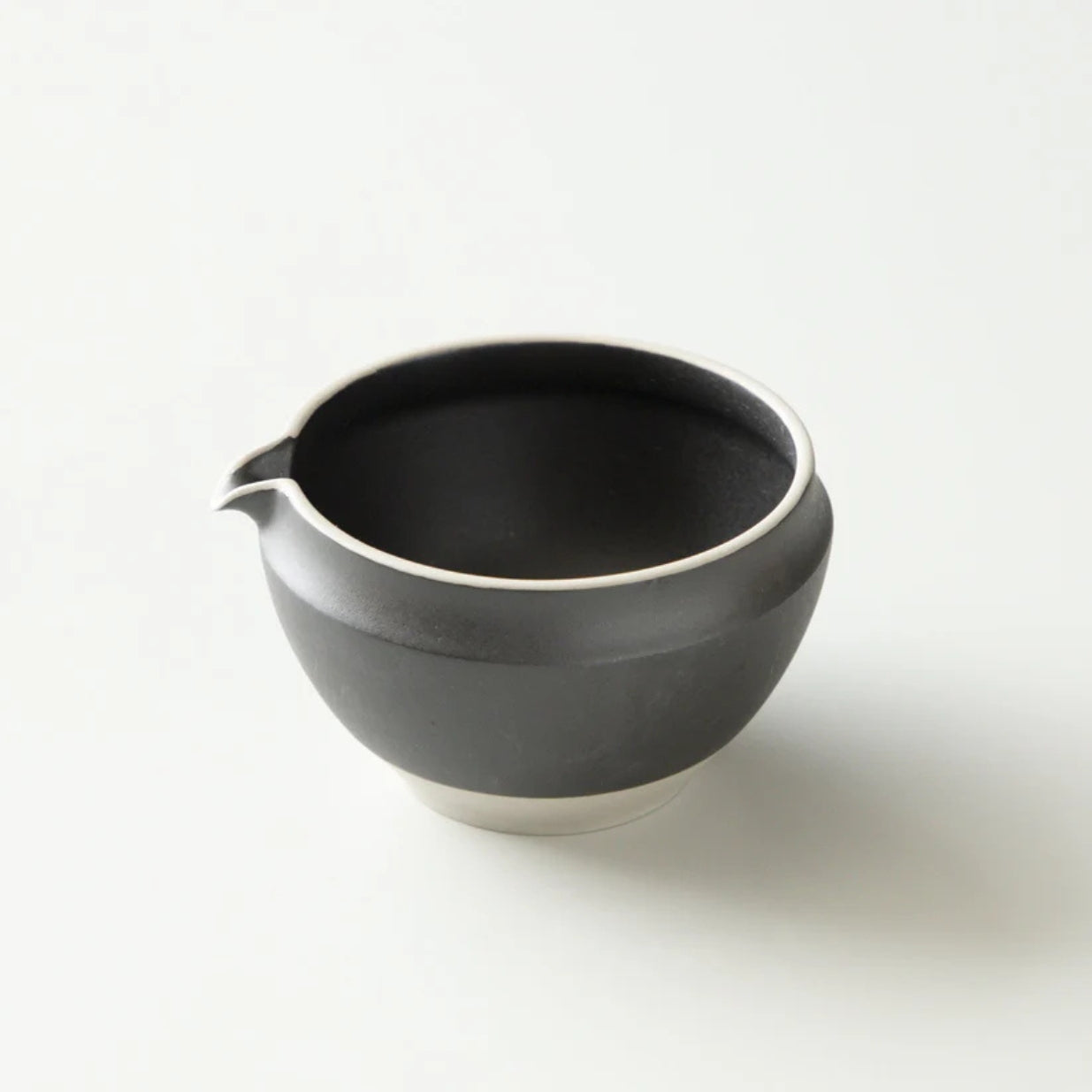 Black ceramic matcha bowl with a spout on a white background