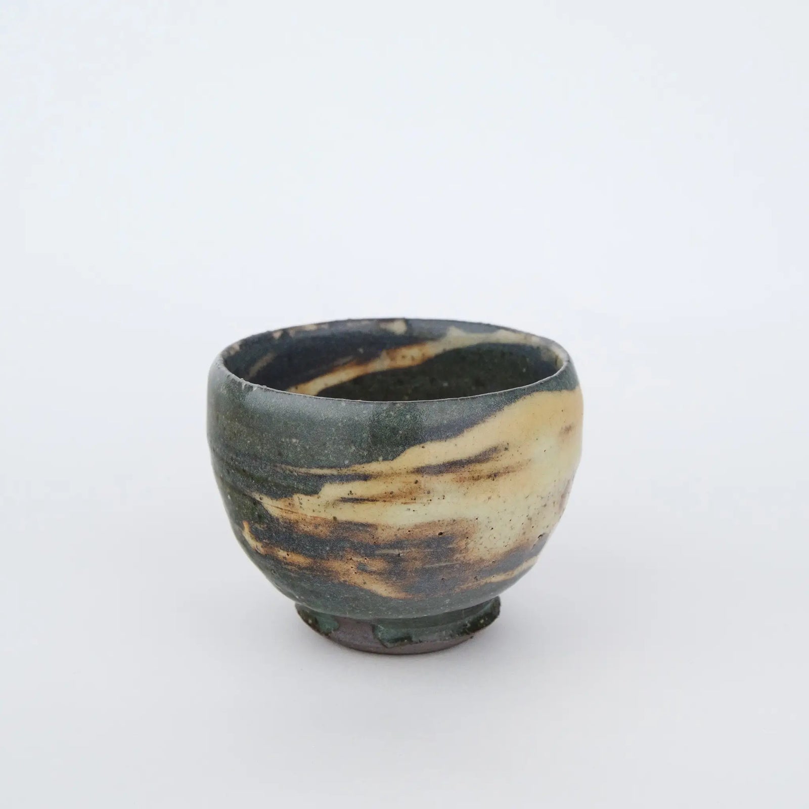 Ceramic cup with a unique glaze pattern on a white background