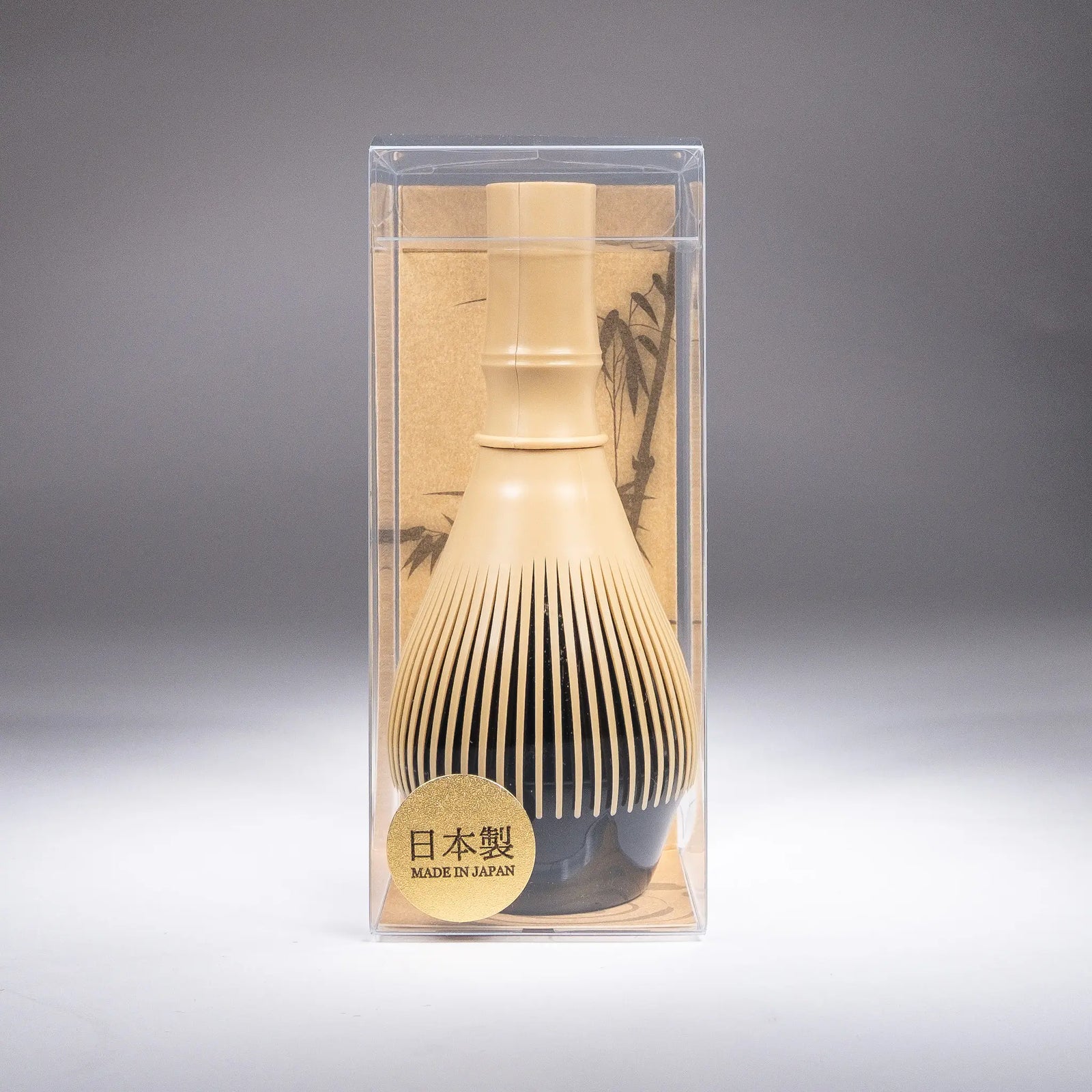 A resin matcha whisk on a stand in plastic box on gray background