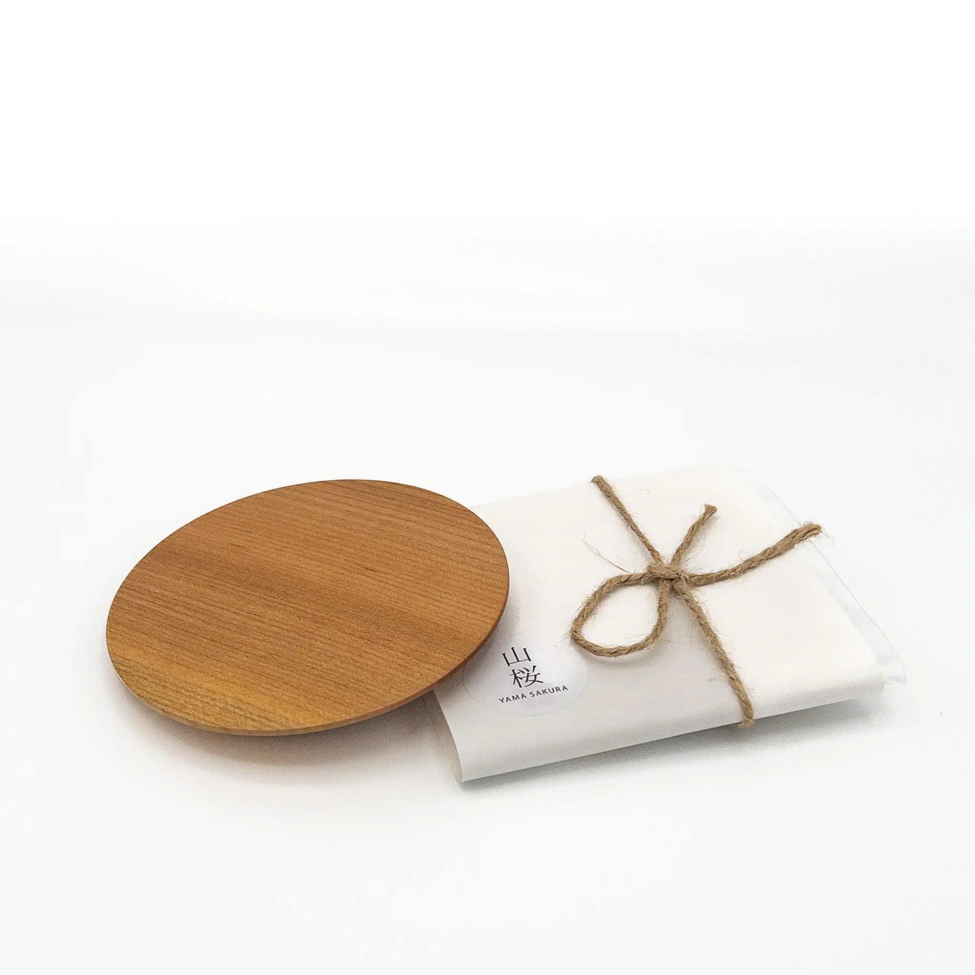 Wooden coaster with a white wrapping and brown string on a white background