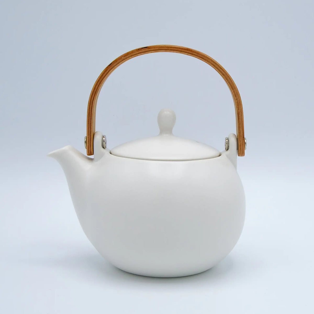 White ceramic teapot with a wooden handle on a light gray background