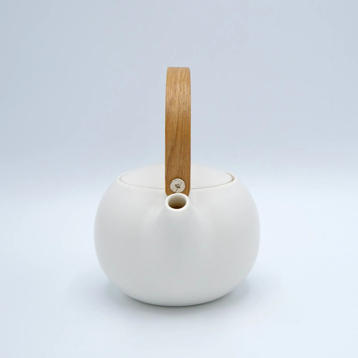 White ceramic teapot with a wooden handle on a light gray background