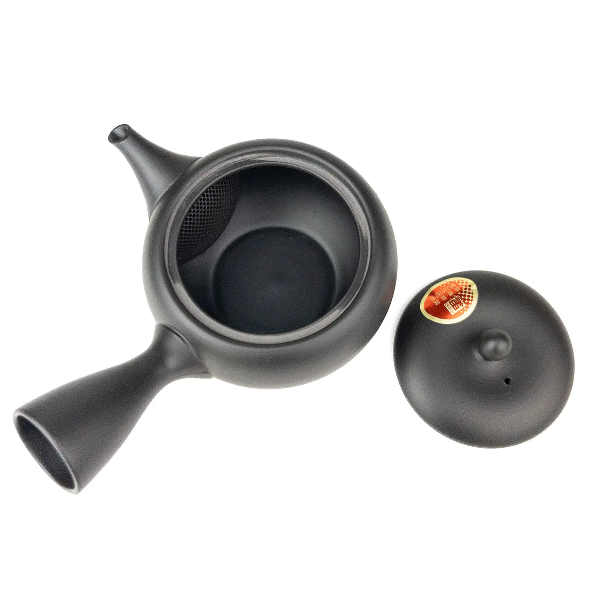 Black ceramic teapot with lid beside it on a white background