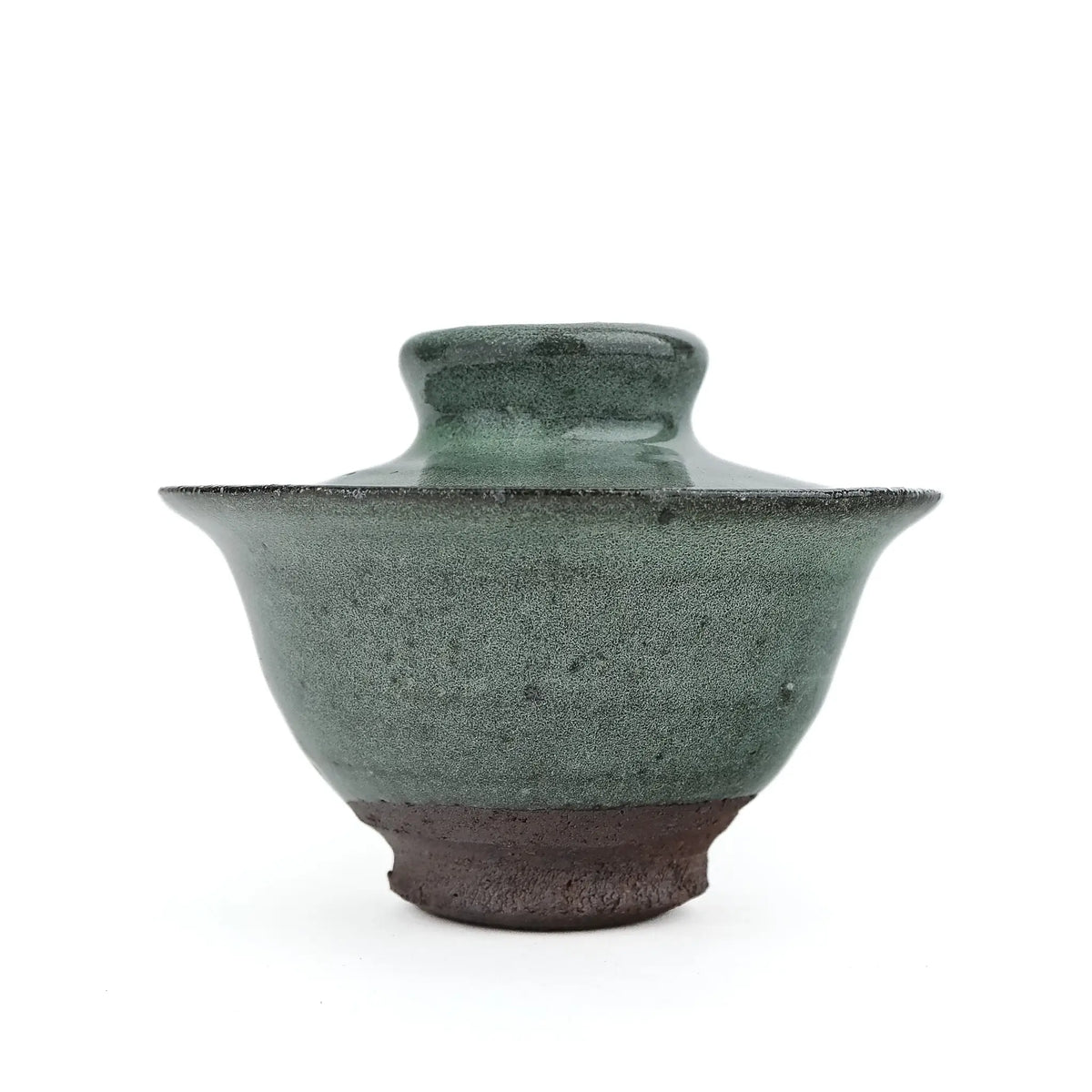 Mark Mohler handmade gaiwan #14 at eye level with the lid on, speckled green glaze on the flared bowl above a wide band of dark unglazed clay at the foot