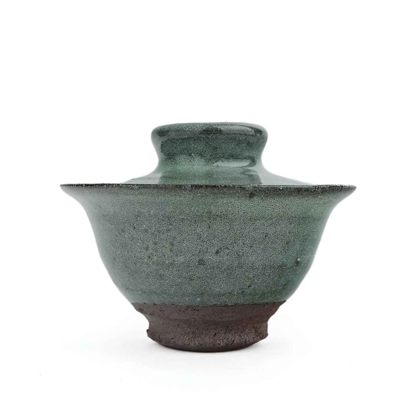 Mark Mohler handmade gaiwan #14 at eye level with the lid on, speckled green glaze on the flared bowl above a wide band of dark unglazed clay at the foot