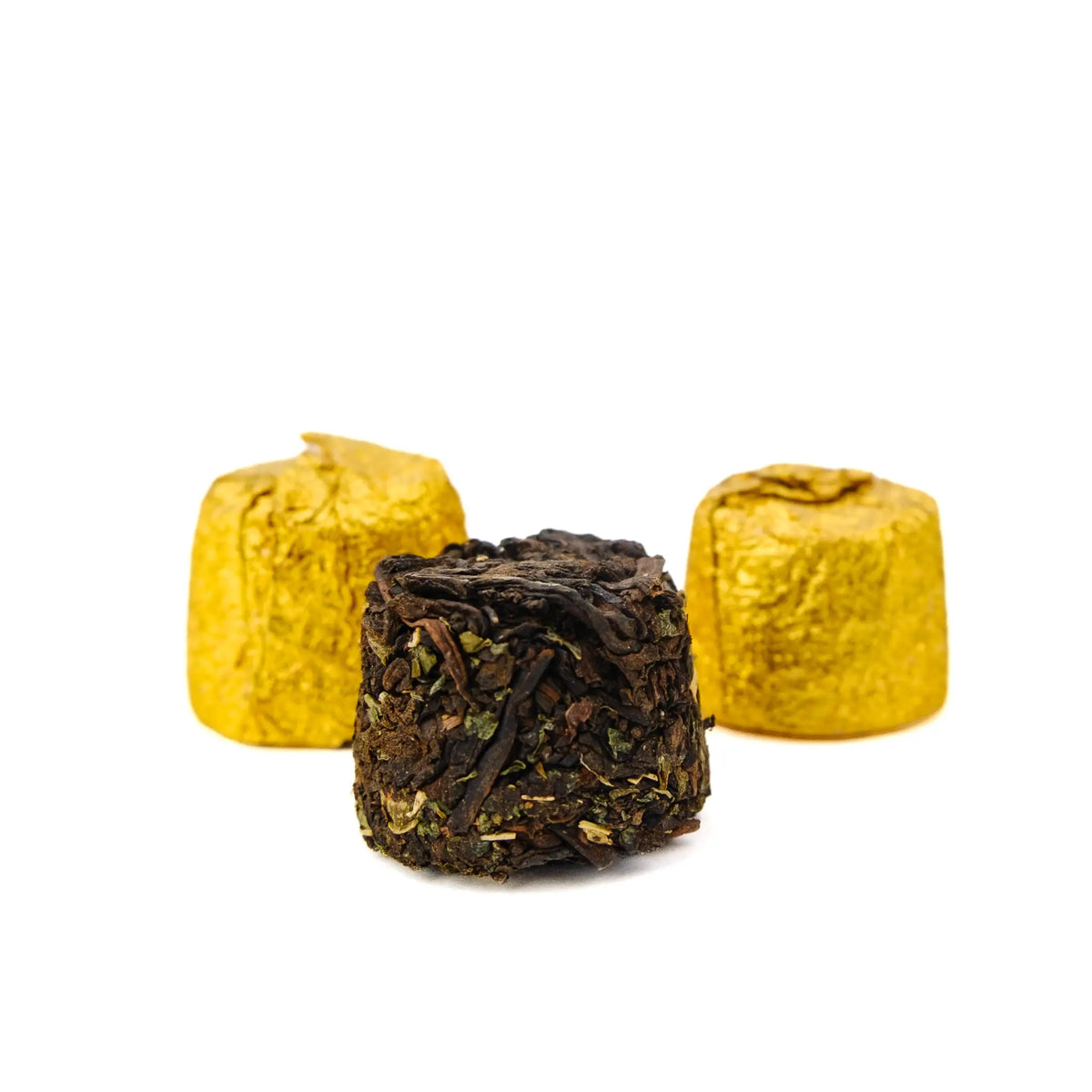 Three Sticky Rice ripe puerh mini tuocha, one unwrapped showing compressed dark leaf and green herb pieces, two still in gold foil